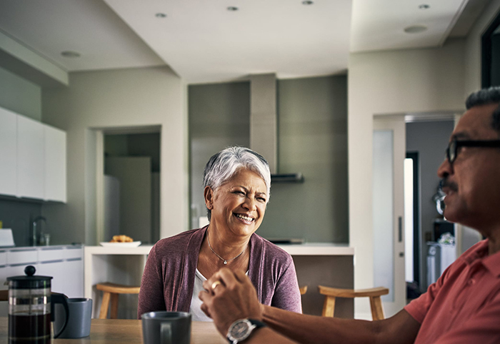man and woman sit together at a table in a home, laughing