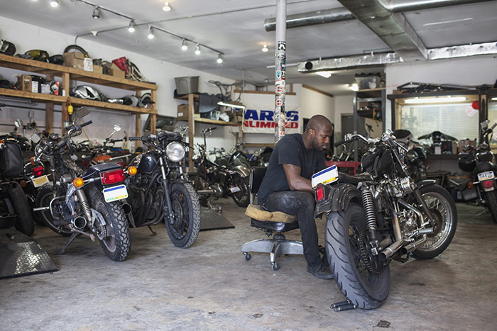 a man is in a garage, working on a motorcycle