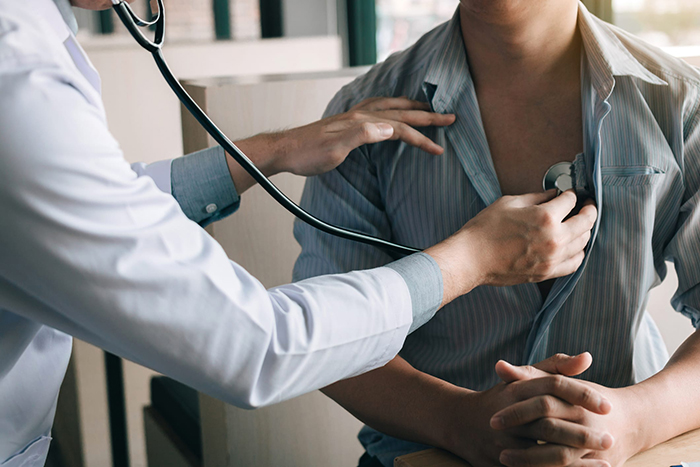 a primary care physician listens to a patient’s heartbeat