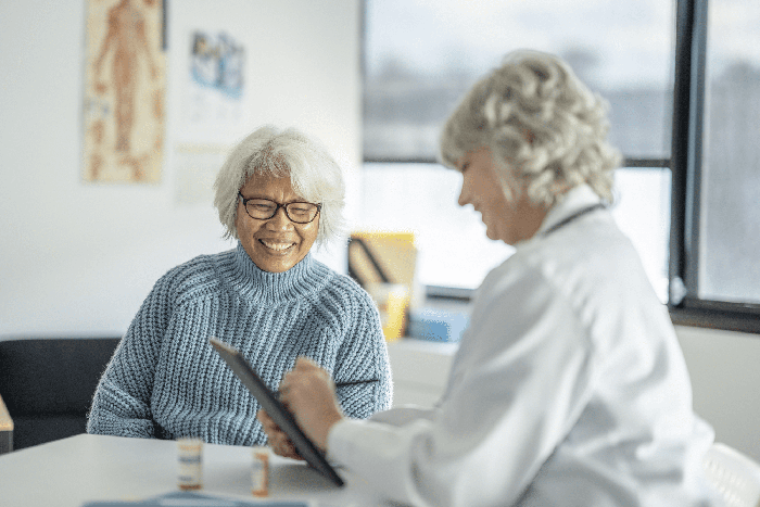 Doctor smiles and fills in chart while talking to senior patient