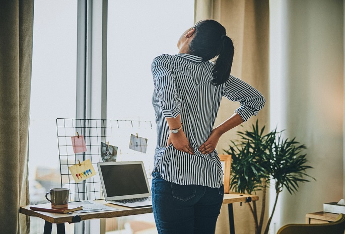 woman holds lower back in pain