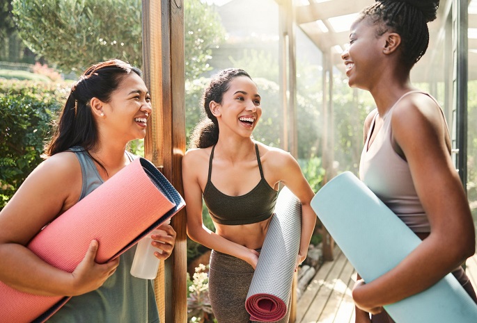 three women smiling and talking at yoga class