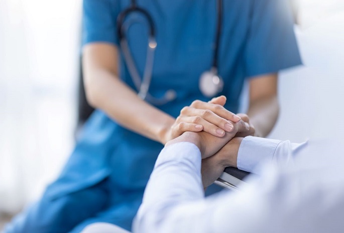 closeup of health provider reassuringly holding hands of patient