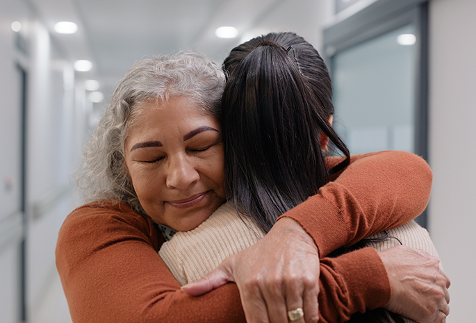 mother and daughter share emotional embrace in hospital hallway