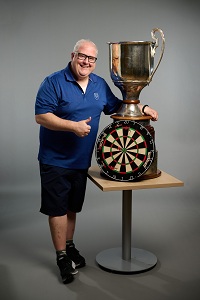 Wade stands next to his darts trophy