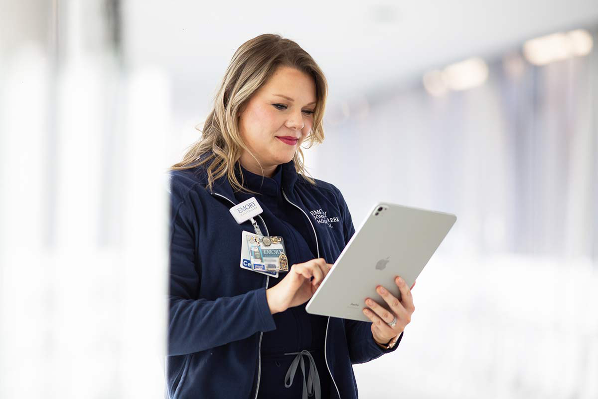 RN looking at iPad in hospital hallway.