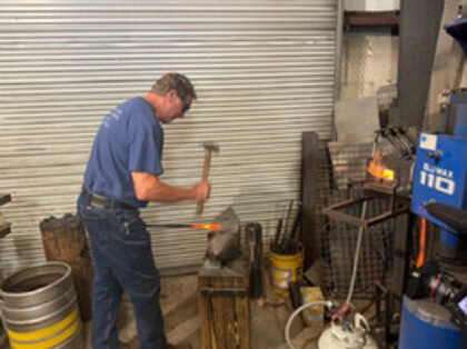 Carl Moore working with a hammer and anvil