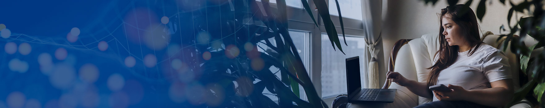 Woman using her laptop computer while holding her phone