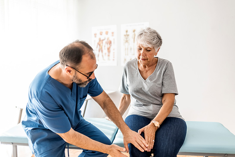 nurse examining elderly woman's knee